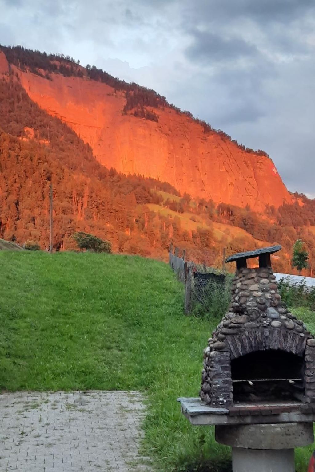 Fornet de pedra a l'aire lliure en un camp de gespa amb una muntanya al fons.