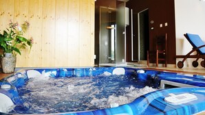 Una bañera de hidromasaje en una habitación con paredes de madera y un sillón azul.