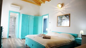 Un dormitorio con cama, mesita de noche, lámpara de pared, un cuadro y una puerta que da a una zona de ducha.