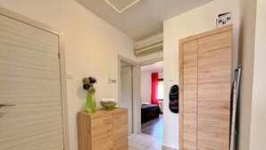 Ein Flur mit einem Holzschrank, einer Vase mit Blumen und einem Bett im Hintergrund.