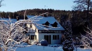 Ein Haus mit geneigtem Dach, einer Garage und einem von Schnee bedeckten Garten.
