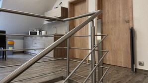 Een moderne keuken met een stalen trap die leidt naar een houten deur.