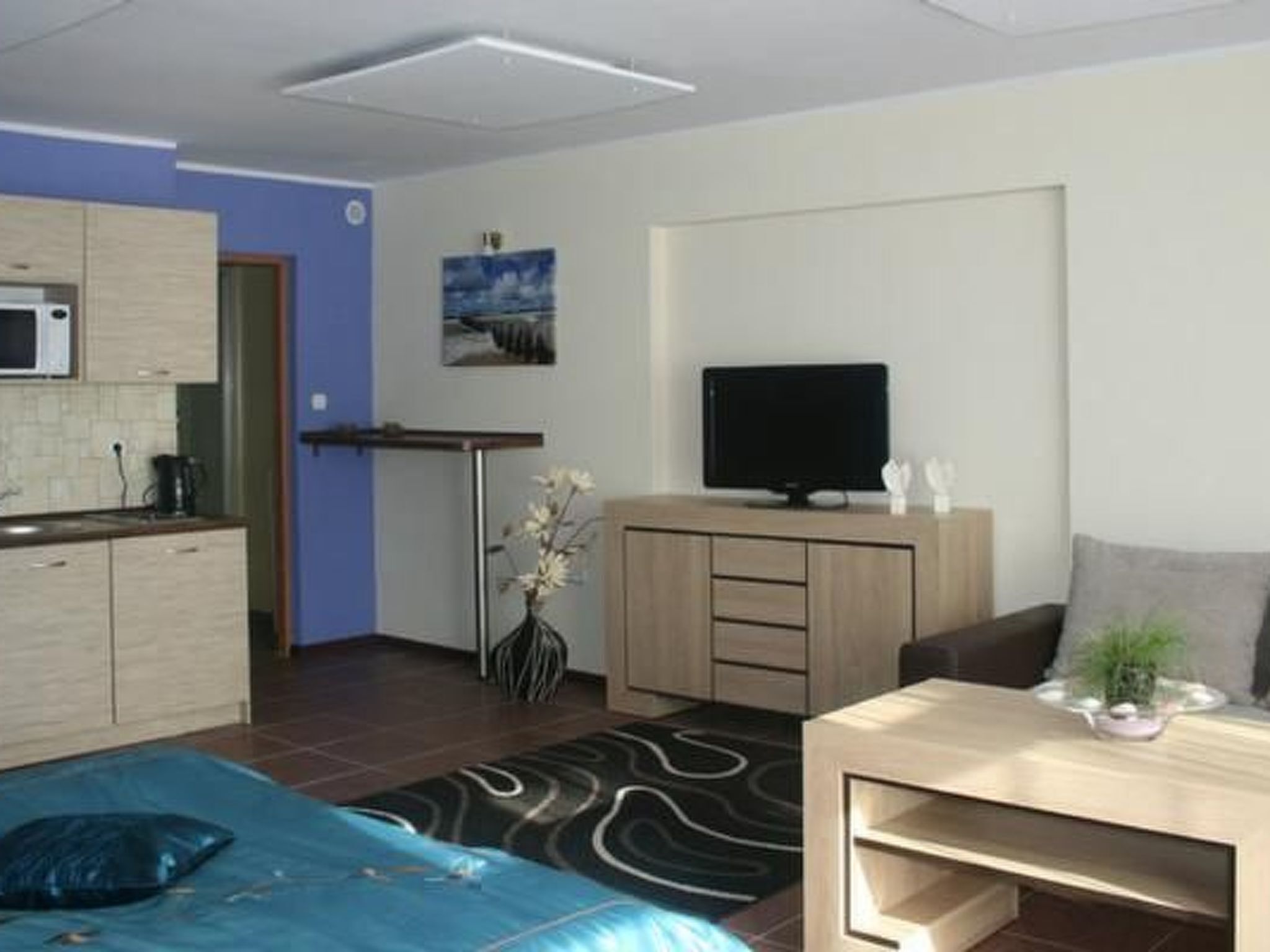 Una camera d'albergo moderna con un letto, una TV, un angolo cottura e un tavolo da pranzo.