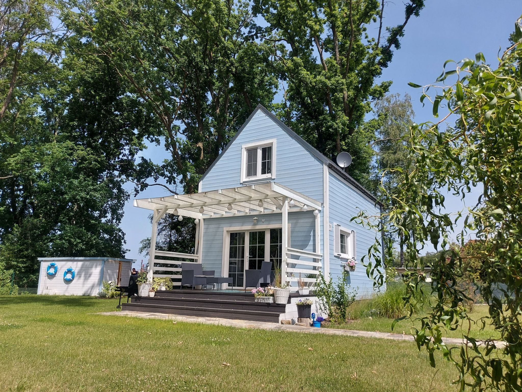A light blue house with a covered porch and a satellite dish.