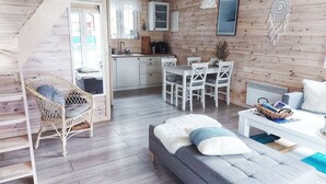 L’intérieur d’un chalet accueillant comprend un coin repas, une cuisine et un canapé gris agrémenté de coussins.