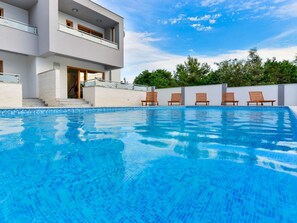 A modern two-story building with a swimming pool, wooden deck chairs, and a clear blue sky. - Villa mit Dachterrasse und Pool - Agentur TA Leut by Interhome (Zaton)