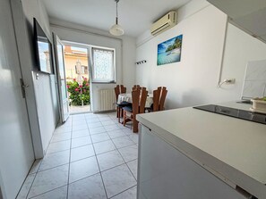 Eine Küche mit Essbereich, einer offenen Tür nach draußen und Außenblick.
