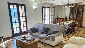 Una sala de estar con un sofá, una mesa de centro, una mesa de comedor con sillas y una araña.