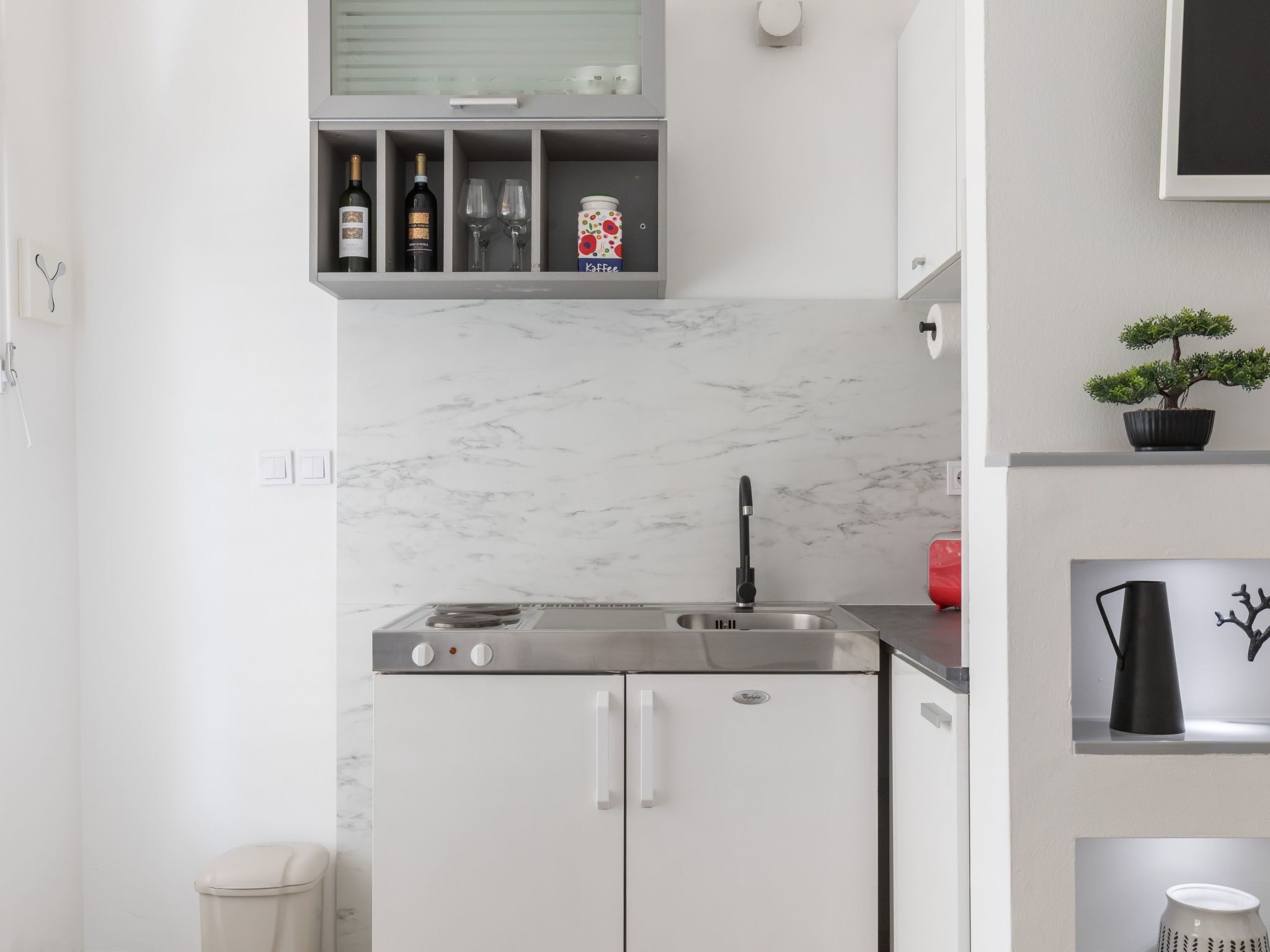 Una cocina moderna con un refrigerador para vinos empotrado, un fregadero y una encimera con una planta en maceta.