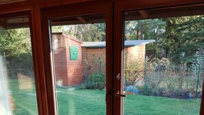 Ein Zimmer mit einer großen Schiebetür und Zugang zu einem Hinterhof mit einer Holzdielen-Terrasse und einem Backsteinbau.