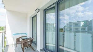 Ein Balkon mit Glastür, Korbmöbeln und einem kleinen Tisch.