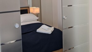 Ein modernes Schlafzimmer mit Bett, Nachttisch, Lampe und einem Schrank mit Schiebetür.