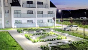 Ein modernes Gebäude mit mehreren Balkonen und einem gut beleuchteten Garten.