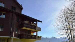 A two-story building with a balcony, surrounded by greenery and mountains in the background. - Haus Ahorni by Interhome (Beatenberg)