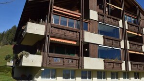 A multi-story building with balconies, large windows, and a stone foundation. - Haus Ahorni by Interhome (Beatenberg)