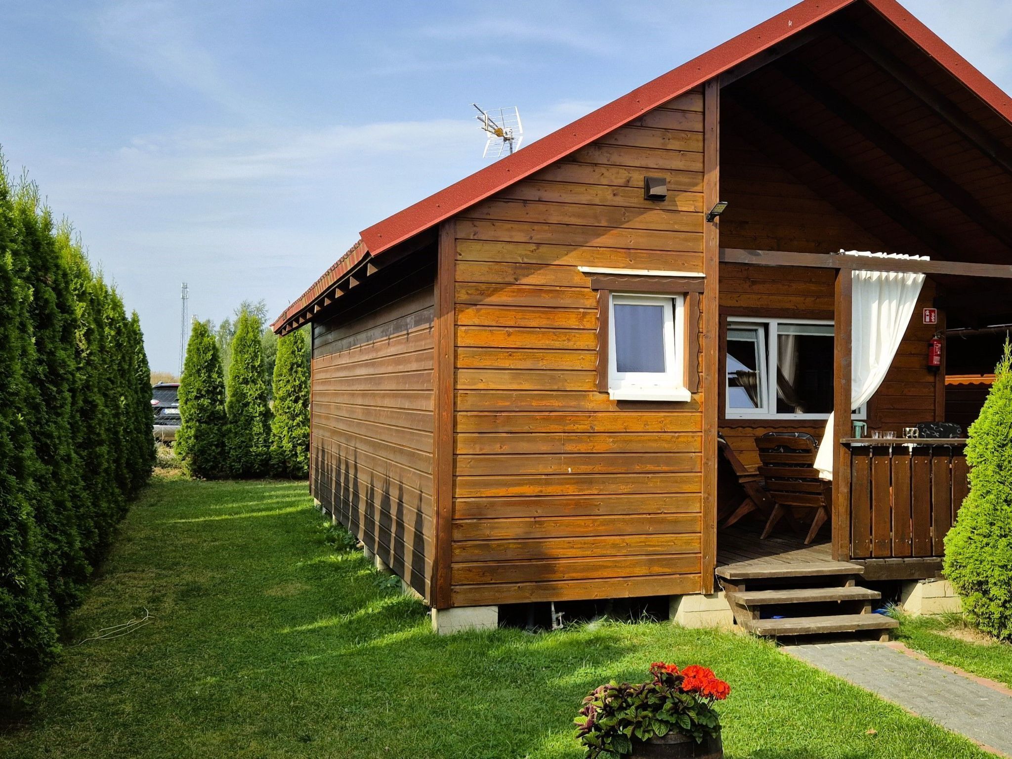 Une cabane en bois avec un toit en pente, une petite véranda et une fenêtre.