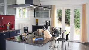 A modern kitchen with a central island, stainless steel appliances, and a view of greenery outside. - Gais Alpins by Interhome (Montreux)