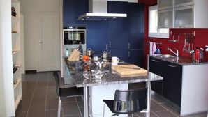 A modern kitchen with a central island, stainless steel appliances, and a red accent wall. - Gais Alpins by Interhome (Montreux)