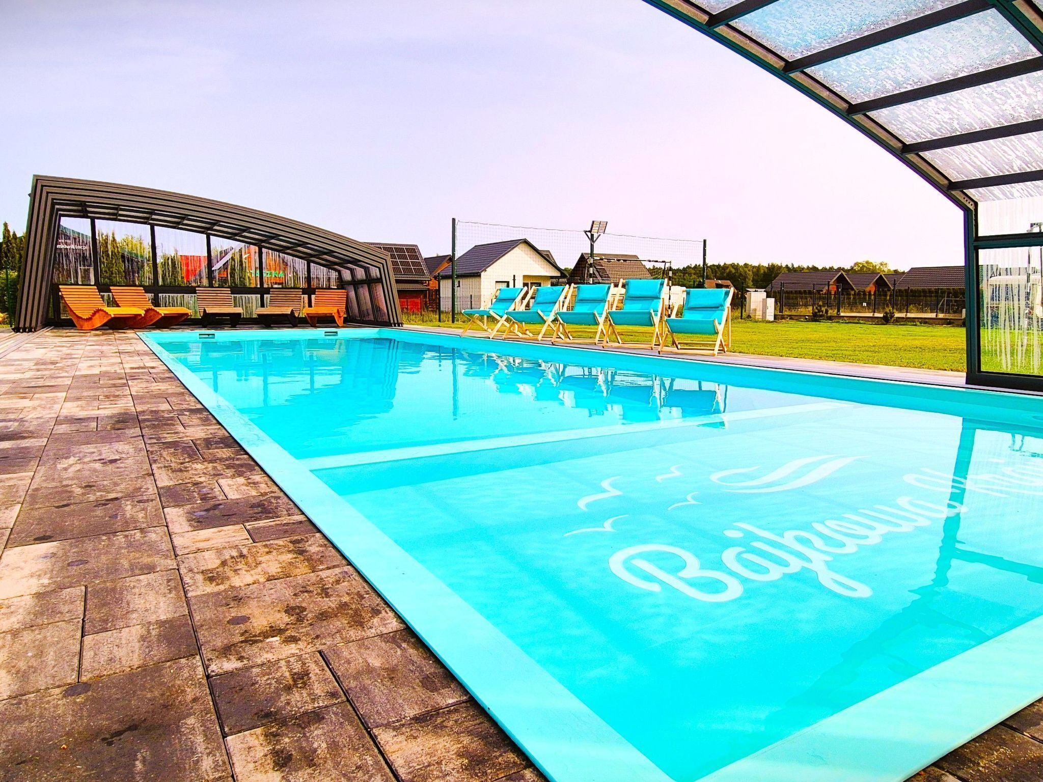 A swimming pool with lounge chairs and a covered area.