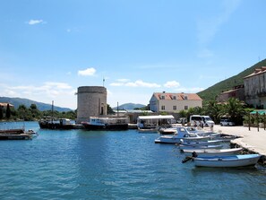 Ein Hafen mit Booten, einem historischen Turm und einem Gebäude mit rotem Dach.