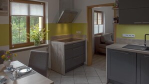 A compact kitchen with a dining area, a built-in stove, and a window with blinds. - Appartement mit Bergblick by Interhome (Bad Elster)