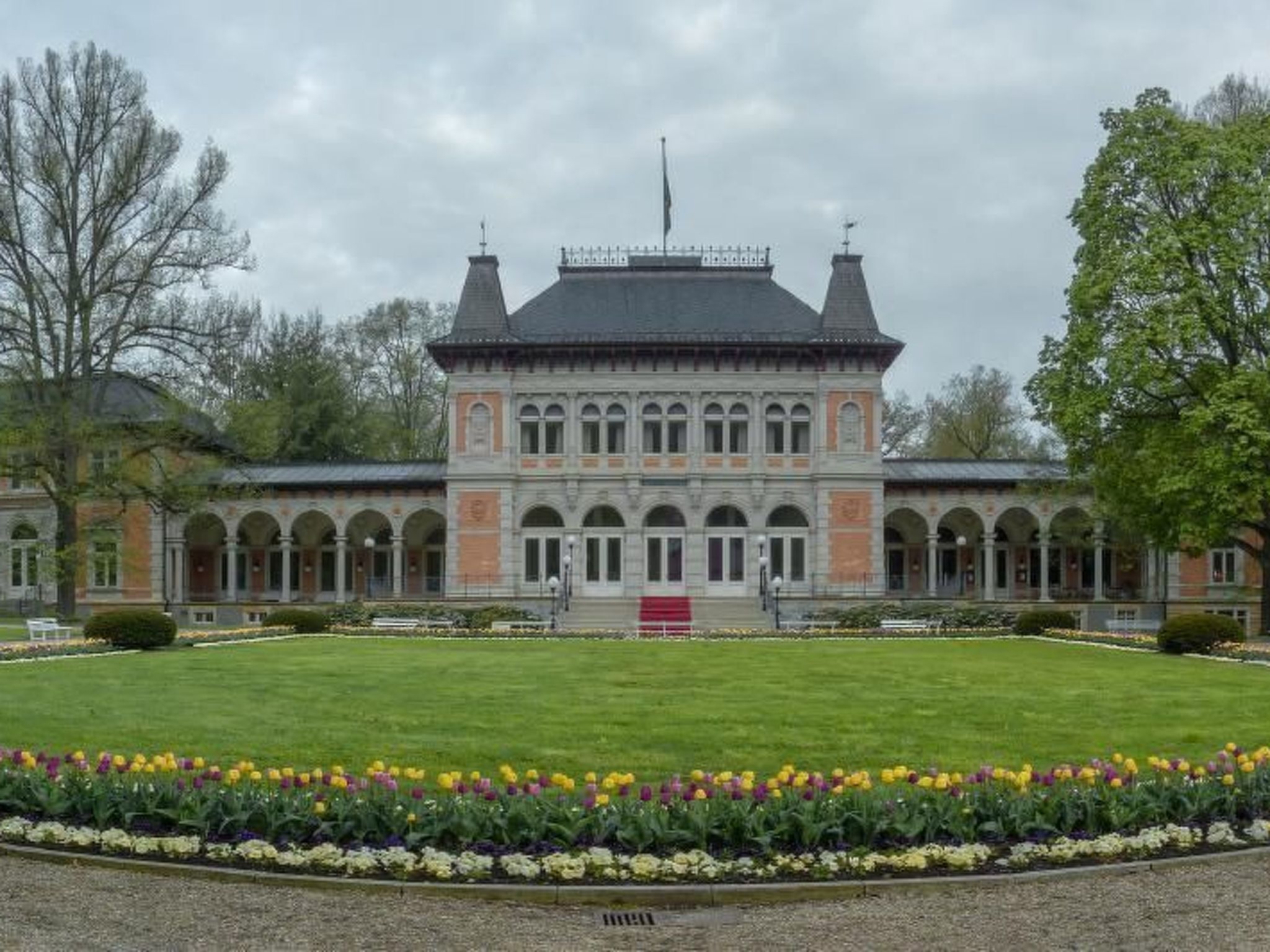 A large, historic building with a symmetrical facade, arched windows, and a central entrance.