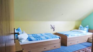Une chambre à coucher avec deux lits simples, chacun recouvert d’une couverture à carreaux bleus et blancs, dotée de têtes de lit en bois et agrémentée d’une petite décoration murale.