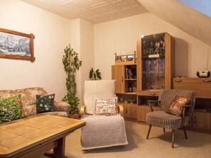 Un salon confortable avec un canapé, un fauteuil, une table basse et une bibliothèque.