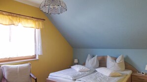 Ein Schlafzimmer mit Bett, Stuhl, Nachttisch und Lampe.
