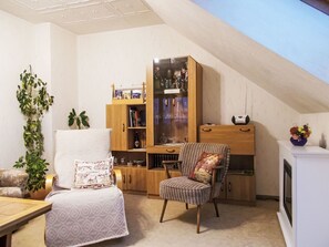 Una sala acogedora con techo alto, una estantería de madera, un sillón estampado y una mesita.