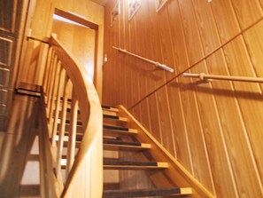 Un escalier en bois, doté d’une rampe et d’une porte en haut.