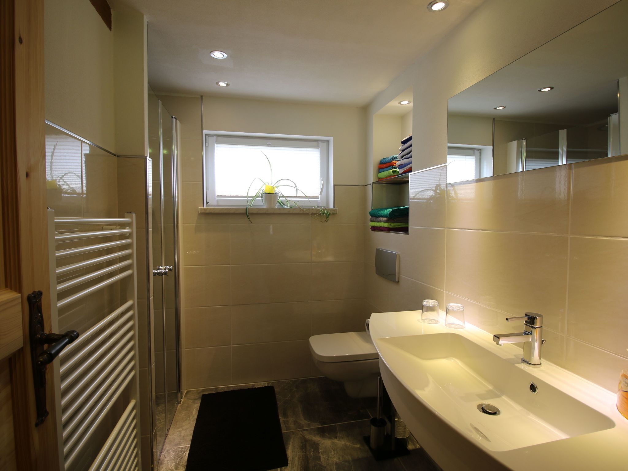 Un baño moderno con un lavamanos blanco, un inodoro y una cabina de ducha de cristal.