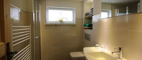 Un baño moderno con un lavamanos blanco, un inodoro y una cabina de ducha de cristal.