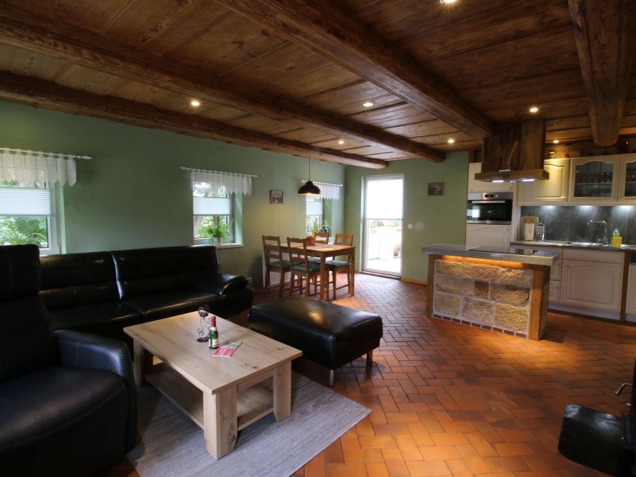 A cozy living room with a sofa, a coffee table, and a dining area with a table and chairs. There is a kitchen area with cabinets and a countertop.