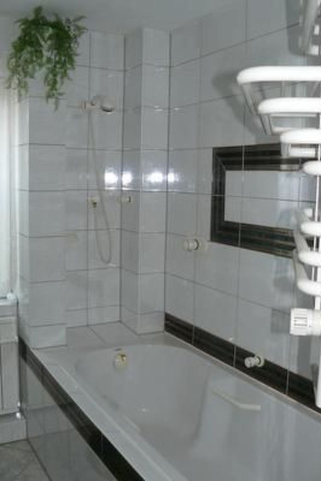 A bathroom with a bathtub, a shower, and a mirror.