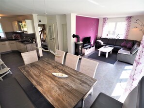 A modern living space with a dining area, kitchen, and a seating area with a sofa and TV. - Traumhafte Reetdach-Doppelhaushälfte mit Garten by Interhome (Rerik)