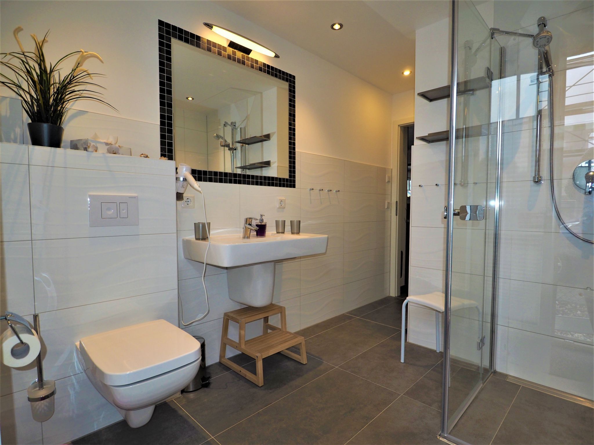 Une salle de bain moderne équipée de toilettes, d’un lavabo et d’une douche.