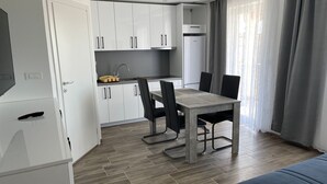 Uma cozinha moderna com armários brancos, forno embutido e uma área de refeições com mesa e cadeiras.