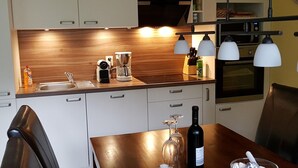 Une cuisine moderne avec un plan de travail en bois, une machine à café, une bouteille de vin et une table à manger avec des chaises.