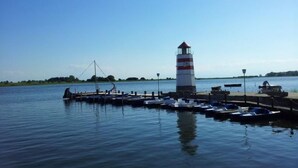 Un phare se dresse sur un quai, à proximité duquel se trouvent plusieurs bateaux amarrés.