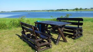 Un coin pique-nique aménagé avec des bancs et une table près d’un lac.