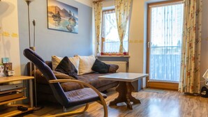 Ein Wohnzimmer mit braunem Sofa, einem Schaukelstuhl, einem Couchtisch aus Holz und einer Stehlampe.