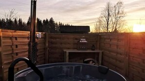 Un jacuzzi en un recinto de madera con una mesa y una tetera.