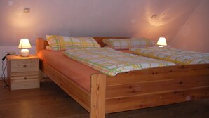 Een houten bed met een bijpassend nachtkastje, twee lampen en een wandlamp.