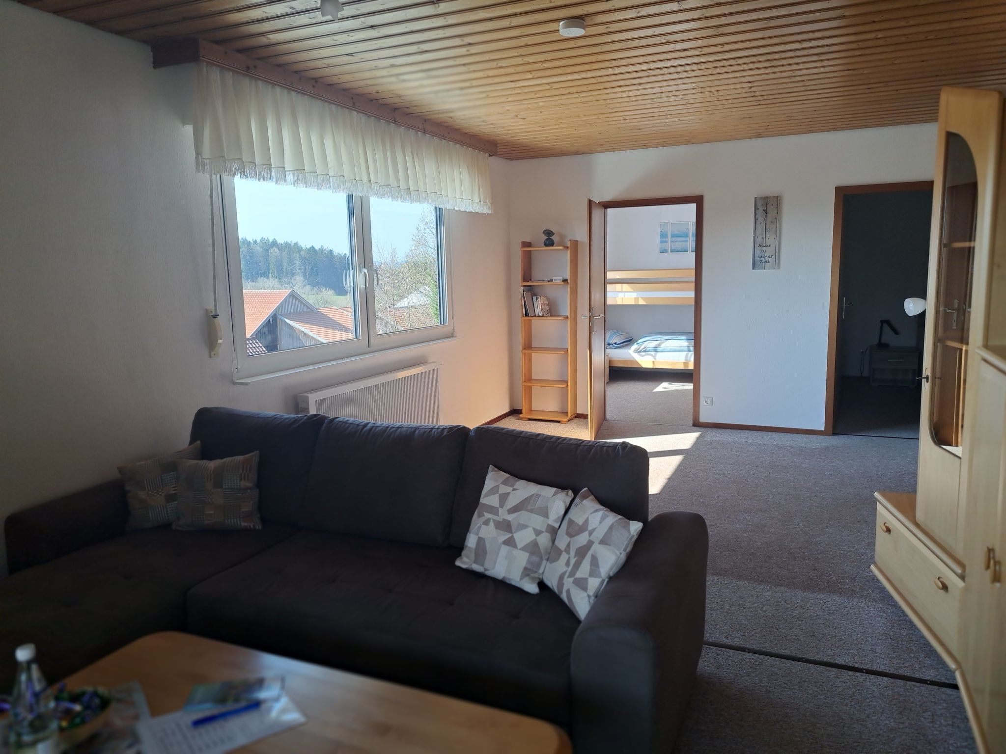 En hyggelig stue med en mørk sofa, et træbord og et vindue med udsigt til bygninger.