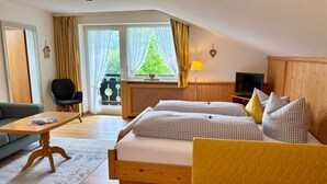 Une chambre d’hôtel avec un lit, un canapé, une télévision et une fenêtre avec des rideaux.