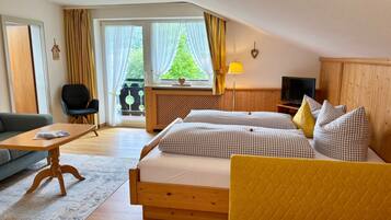 Ein Hotelzimmer mit Bett, Sofa, Fernseher und einem Fenster mit Vorhängen.