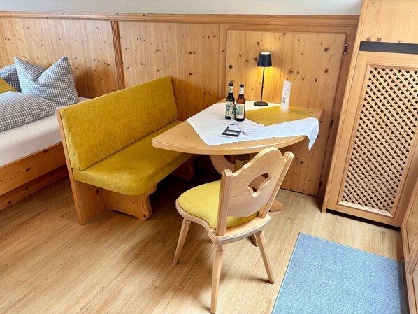 Une pièce chaleureuse avec un lit superposé en bois, un canapé jaune, une table en bois avec une lampe et une chaise.