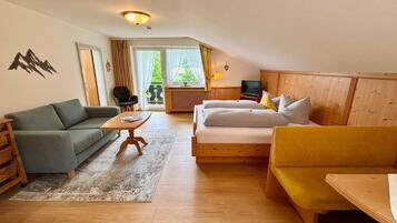Ein gemütliches Zimmer mit einer Couch, einem Bett, einem Tisch und einem Fernseher.