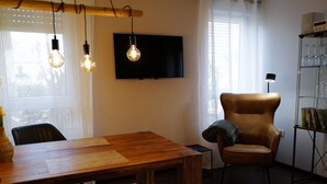 Una sala de estar moderna con una mesa de comedor de madera, un sillón de cuero y un televisor de pantalla plana montado en la pared.